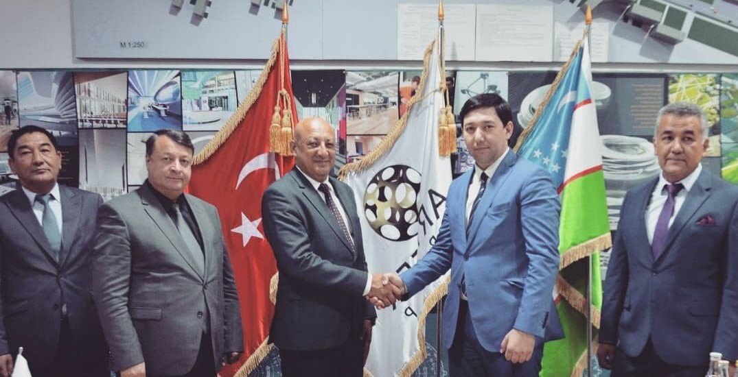 Rustam Khaitmetov with partners at an international signing, Uzbek and Turkish flags
